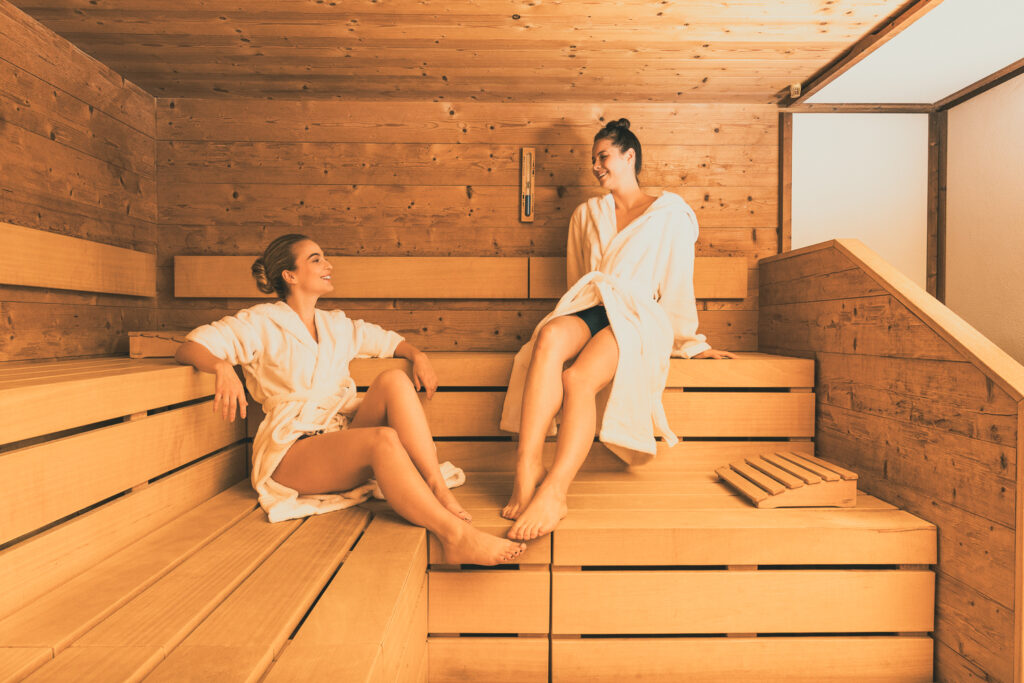 Gemütliche Stunden in der eigenen Sauna: Eine junge Frau genießt die wohltuende Wärme mit einer Freundin. Sauna bauen mit Tischler Franz Sieberer in Wien Umgebung.