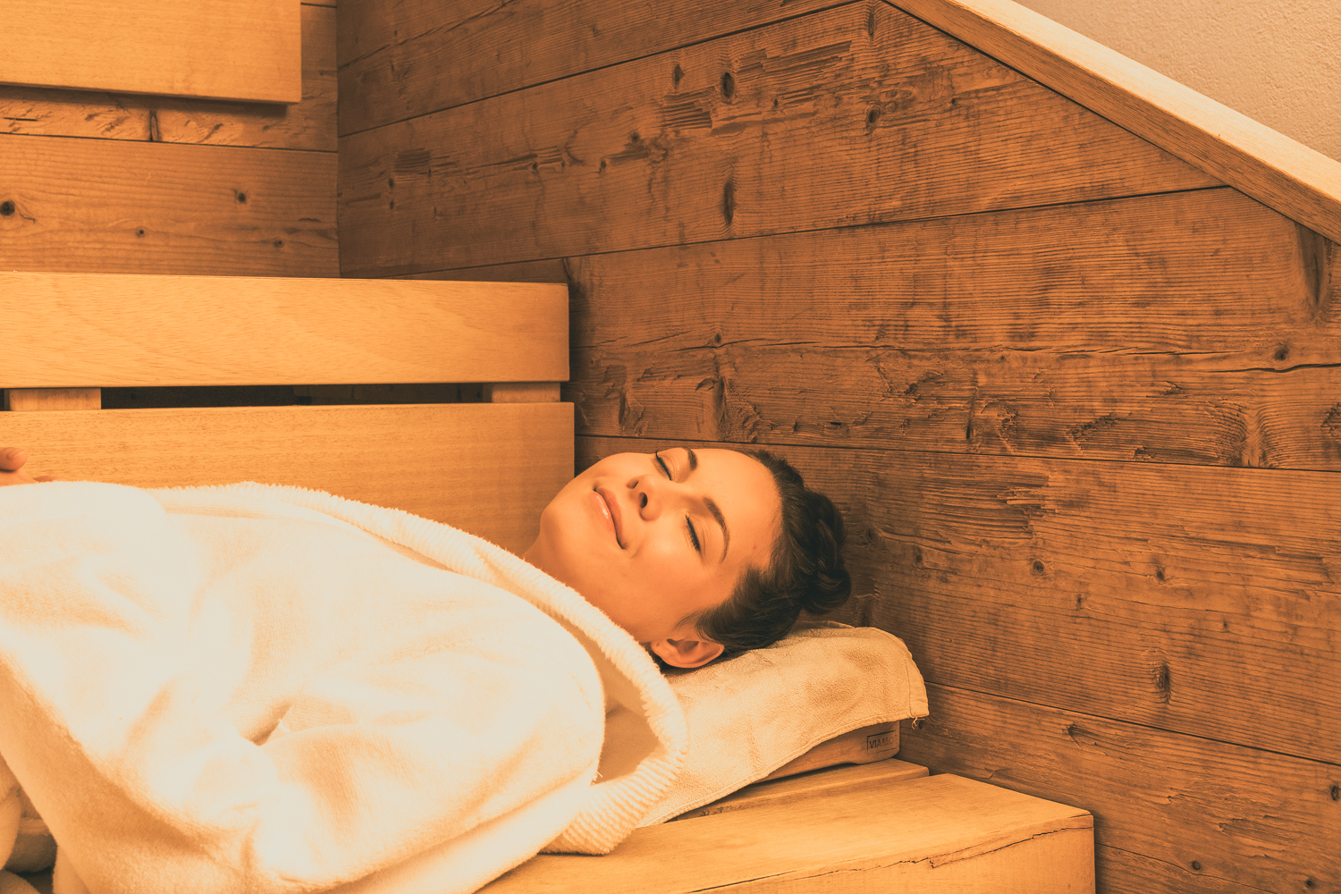 Wohlfühlatmosphäre in der Sauna: Eine junge Frau genießt die angenehme Wärme. Hochwertiger Saunabau von Tischler Franz Sieberer.