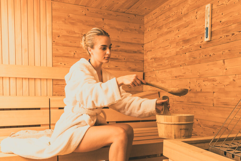 Eine junge Frau entspannt in der angenehmen Wärme einer Sauna – maßgefertigter Saunabau von Tischler Franz Sieberer in Österreich.